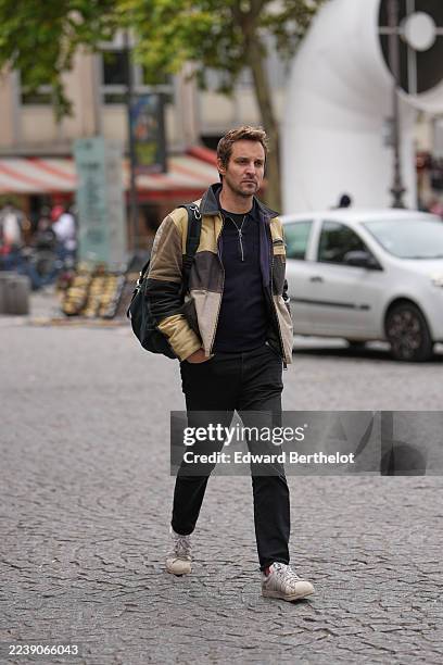 Guest wears a black t-shirt, a black zipper neck pullover, a yellow / brown /beige shiny leather patchwork jacket, black pants, white leather...