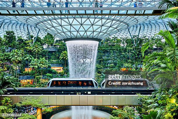 rain vortex and shopping mall & railway train at changi airport, singapore - changi airport stock pictures, royalty-free photos & images