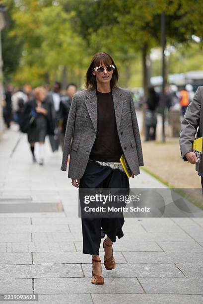 Guest is seen wearing a single-breasted structured checked blazer in grey, worn draped over the shoulders; a dark brown crewneck sweater with ribbed...