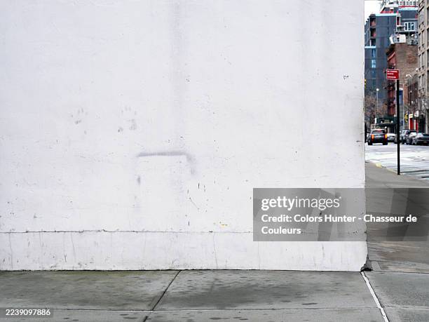 a white concrete wall at the corner of a street in manhattan, new york state, united state. cement sidewalk. no people.sunlight. natural colors. - cement sidewalk stock pictures, royalty-free photos & images