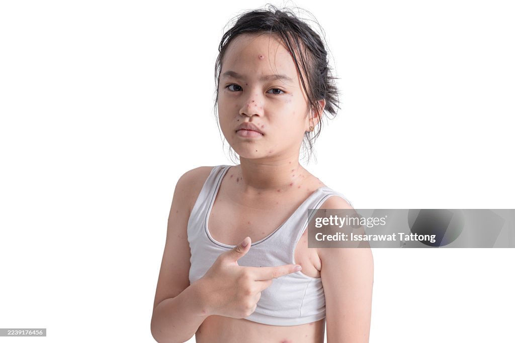 A young girl with a white shirt and black hair is pointing to her chest