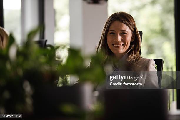 une femme d’affaires souriante dans un bureau lumineux crée une atmosphère amicale et productive pour une liste de lieu de travail d’entreprise - high key photos et images de collection