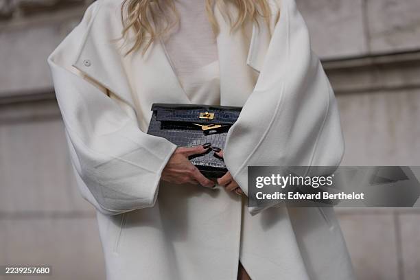 Leonie Hanne wears a black croc-embossed leather Kelly clutch bag from Hermes, a cream high-neck sheer knit top beneath an ivory long oversized wool...