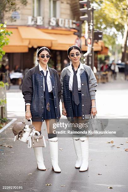 Senehal and Jyoti Babani wear matching preppy looks featuring white shirts with ties, navy pleated mini skirts, grey and navy bomber jackets with...