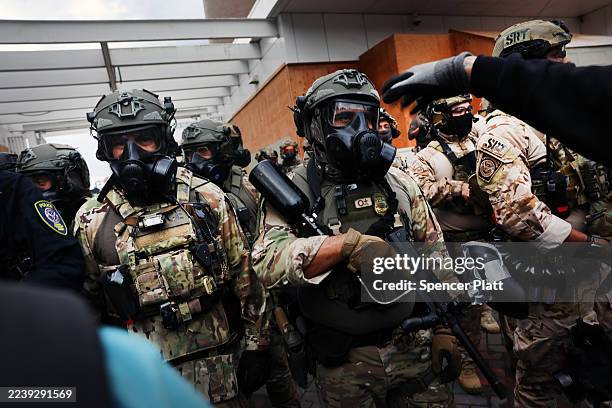 Federal agents, including members of the Department of Homeland Security, the Border Patrol, and police, attempt to keep protesters back outside a...