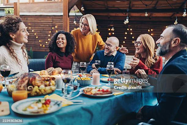 group of smiling mixed age people gathered around the table celebrating - middagsbjudning bildbanksfoton och bilder