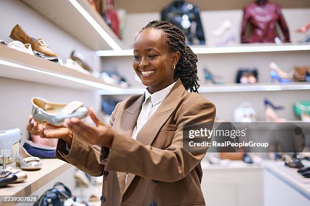 young adult woman holding a shoe in retail store - black shoe stock pictures, royalty-free photos & images