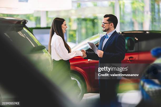 vendedor de coches estrechando la mano de un cliente en un concesionario - accesorio financiero fotografías e imágenes de stock