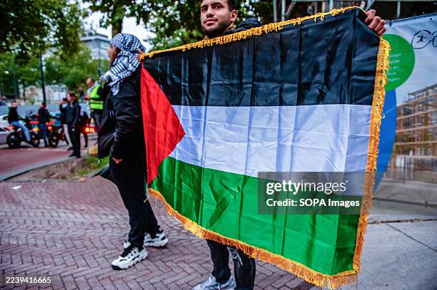 Man is holding a Palestinian flag during the rally. On the day that marks two years of Hamas attacks, and the genocide in Gaza by the Israeli...