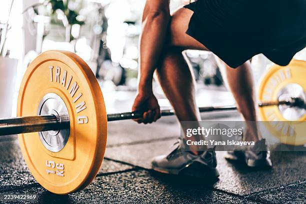 unrecognizable man performing weight lifting in a gym with yellow plates and barbell on rubber flooring - tyngdlyftning bildbanksfoton och bilder