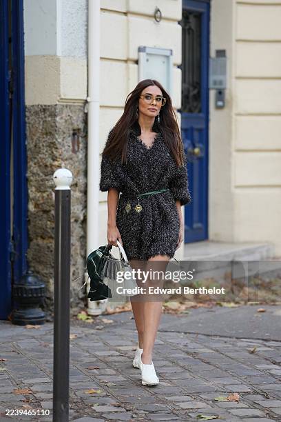 Max Collins wears long straight chestnut brown hair parted down the middle, amber-tinted oversized sunglasses, a white leather top-handle bag with a...