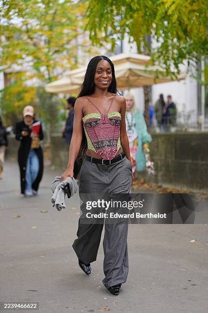 Guest wears long black hair in thin braids with a center part, a structured patchwork printed corset top in burgundy, maroon and lime green featuring...