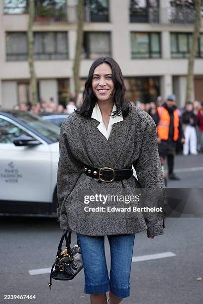 Alexa Chung wears shoulder-length dark brown wavy hair with a center part, a black leather satchel bag from Chloe with top handles, gold-tone...