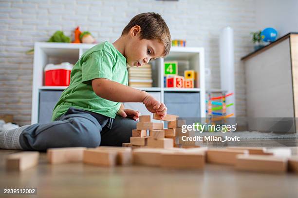 construcción creativa de niños con juguetes de madera en la sala de juegos - jugar fotografías e imágenes de stock