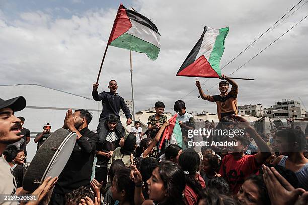 Palestinians, including children, gathered at the Nuseirat refugee camp celebrate with Palestinian flags after the announcement of the ceasefire...