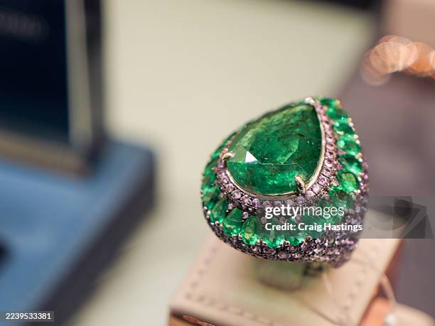 pear-shaped emerald and diamond ring displayed on luxury jewelry stand. - emerald gemstone stock pictures, royalty-free photos & images
