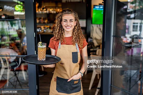 serveuse souriante servant à boire dans un café moderne - tablier photos et images de collection