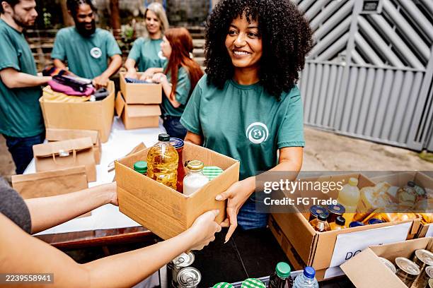 volunteer woman passing donation box outdoors - caridade imagens e fotografias de stock