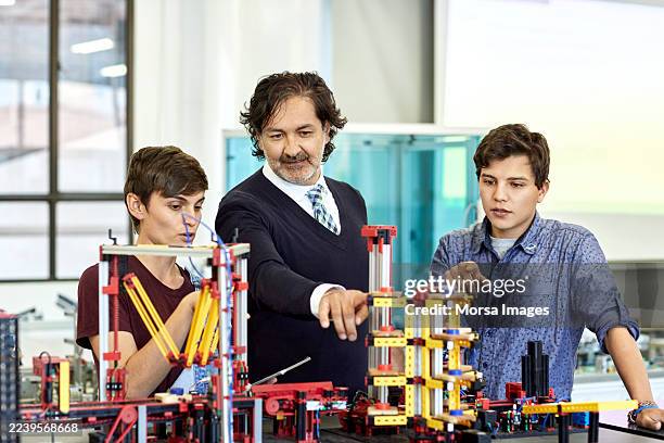 male professor teaching students over model in computer lab - pedagoga imagens e fotografias de stock