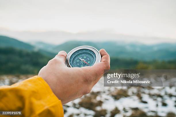 händchenhaltender kompass über berglandschaft während eines outdoor-wanderabenteuers - geländefahren stock-fotos und bilder