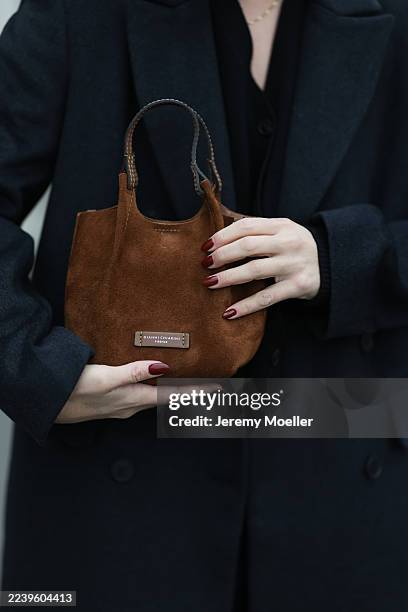 Sonia Lyson with a blonde bun seen wearing Levi’s black wide-leg jeans, a long black wool coat by Lala Berlin, a brown Gianni Chiarini bag, a black...