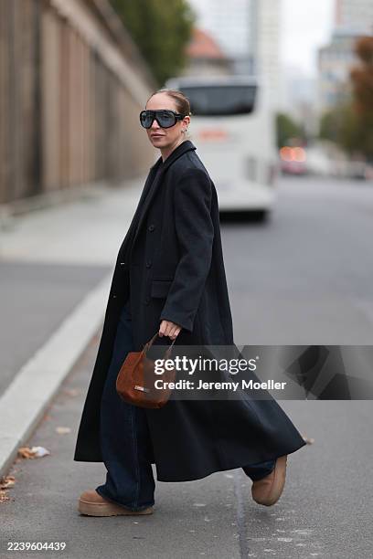 Sonia Lyson with a blonde bun seen wearing Levi’s black wide-leg jeans, a long black wool coat by Lala Berlin, a brown Gianni Chiarini bag, a black...