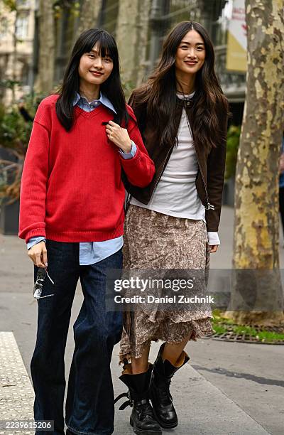 Model Shuqi Lan is seen wearing a red sweater, blue button shirt, dark blue jeans, black shoes with model Xu Wei wearing a brown jacket, white shirt,...