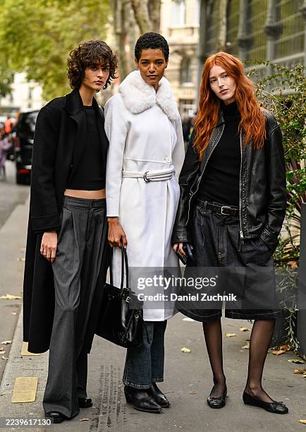 Model Sophia Lisboa is seen wearing a black trench coat, black cropped top, gray pants and black bag with model Laiza de Moura is seen wearing a...