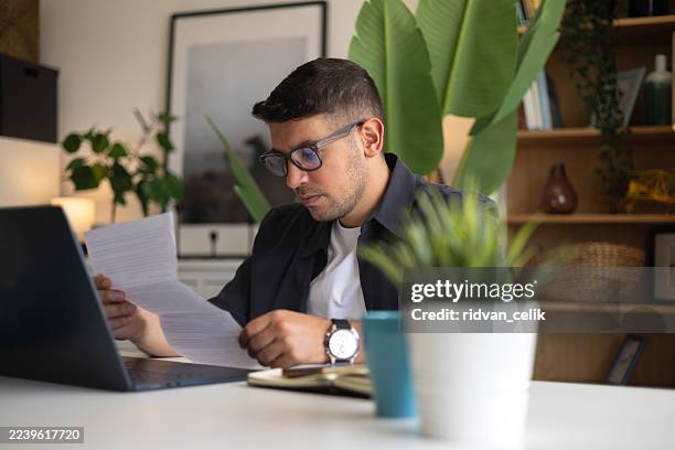 uomo frustrato confuso che legge una lettera nell'ufficio di casa, ricevendo cattive notizie - studio legale foto e immagini stock