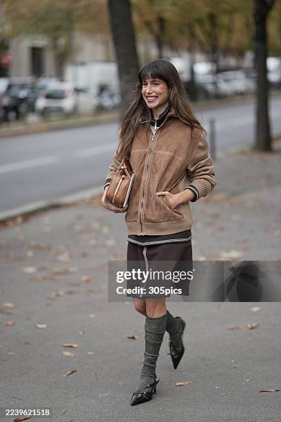 Belen Hostalet is seen wearing black low heels, beige suede Miu Miu jacket, brown midi skirt, grey ribbed socks, black Miu Miu bag, camel Miu Miu bag...