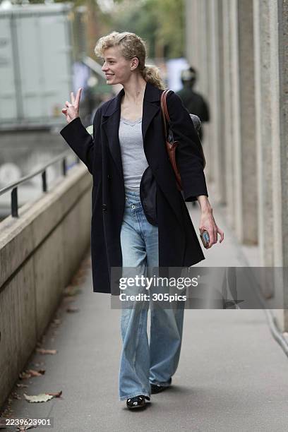 Saar Mansvelt Beck is seen wearing a curly blonde ponytail, a long black coat, a light grey lace-trimmed camisole top, light blue high-waisted...