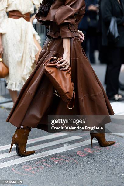 Guest wears a monochrome ensemble in rich cognac brown leather, including a voluminous A-line skirt and a cropped jacket with structured shoulders...