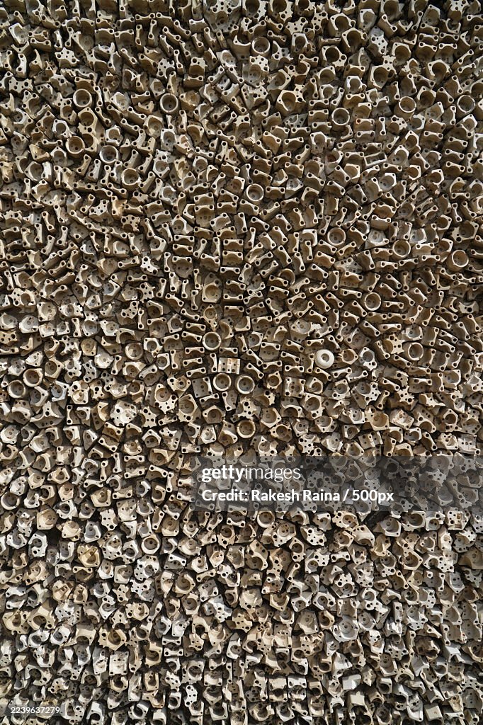 Full frame shot of a dense arrangement of small, aged metal or ceramic components, creating a textured, abstract background