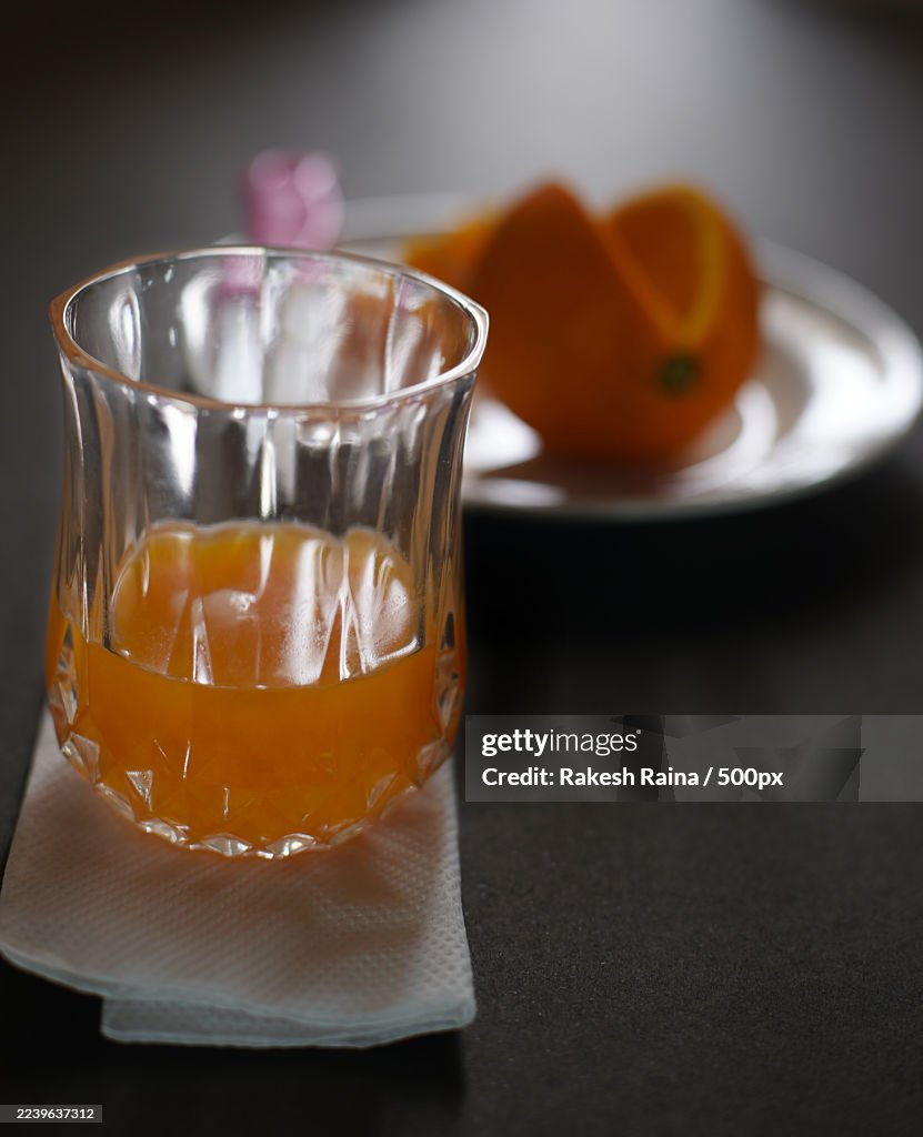 Close-up of a glass of fresh orange juice on a napkin with oranges in the background