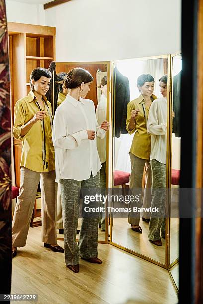 wide shot female customer examining bespoke outfit in dressing room - woman-looking-into-mirror-full-body stock pictures, royalty-free photos & images