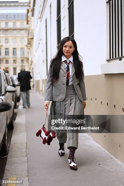 Guest wears long straight black hair with a center part, a burgundy plush velvet dog shape handbag with a gold chain strap, a white collared...