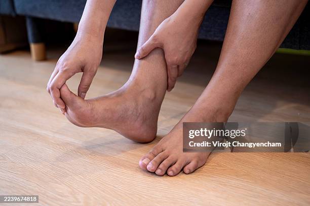 a female has a massages tired legs at home after long working day - orteil photos et images de collection