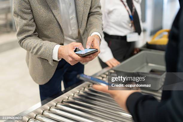 viaggiatori che si preparano per i controlli di sicurezza in aeroporto - controllo foto e immagini stock