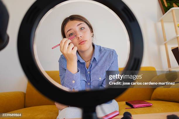 young woman applying makeup looking at camera through ring light - makeup tutorial stock pictures, royalty-free photos & images