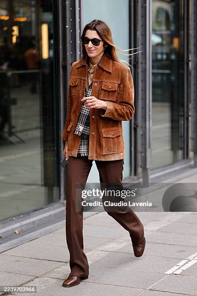 Guest wears beige shirt, brown checked scarf, camel suede jacket, brown trousers, brown boots, outside Coperni, during the Womenswear Spring Summer...
