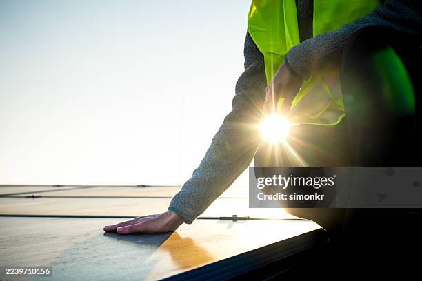 female professional evaluating solar technology on factory rooftop - sun safety stock pictures, royalty-free photos & images