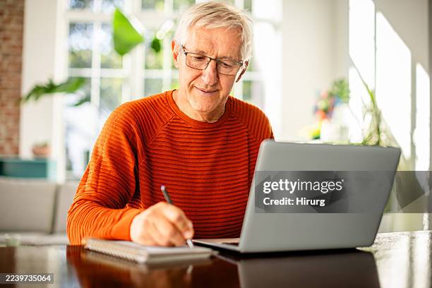 homme âgé profitant d’un temps productif dans le bureau à domicile tout en écrivant et en travaillant sur un ordinateur portable - retraités qui travaillent photos et images de collection