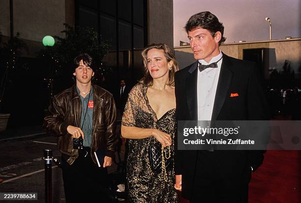 American actress and singer Dana Morosini, wearing a sheer gold evening wrap over a black dress, and her partner, American actor Christopher Reeve,...