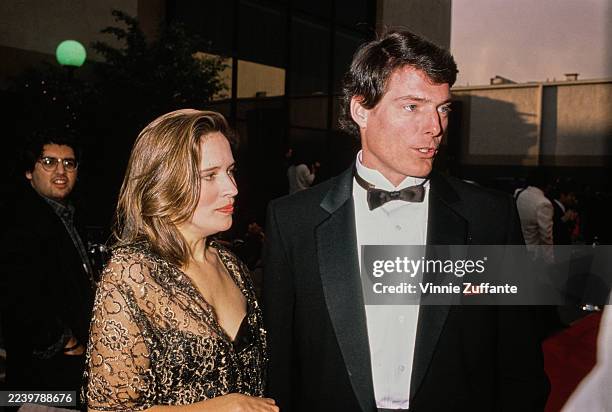 American actress and singer Dana Morosini, wearing a sheer gold evening wrap over a black dress, and her partner, American actor Christopher Reeve,...