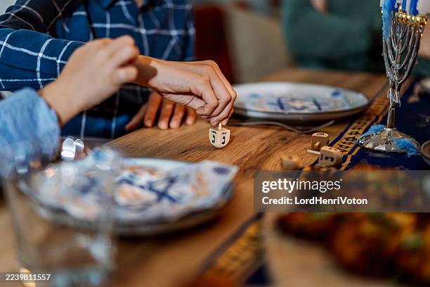child playing dreidel game during hanukkah celebration - dreidel stock pictures, royalty-free photos & images