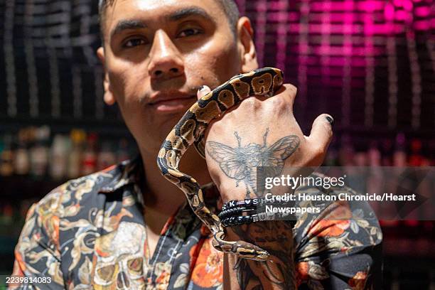 Javier Ramirez holds Dolly Python, a ball python that he adopted after the previous owner lost it in the Secret Group, an EaDo bar and performance...