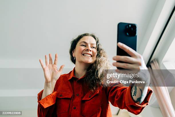 woman smiling and waving during video call on smartphone - self recording stock pictures, royalty-free photos & images