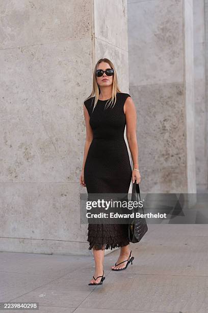 Guest wears long straight blonde hair with a center part, black rectangular sunglasses, a thin silver bracelet, a black quilted leather shoulder bag...