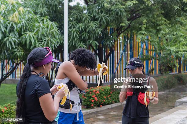 mujeres corredoras comiendo plátanos e hidratándose durante un descanso - carbohidrato fotografías e imágenes de stock
