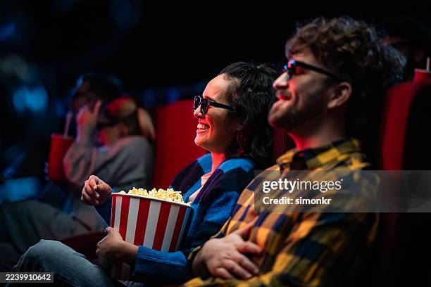 heureux jeune couple hispanique regardant un film 3d et mangeant du pop-corn - lunettes 3d photos et images de collection